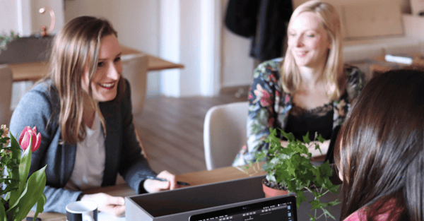 Three women working on their computers and talking