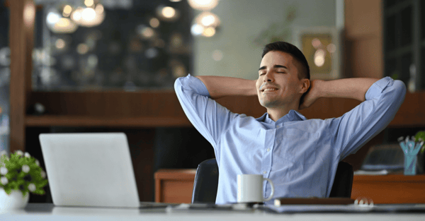 A person in a office smiling at the computer.