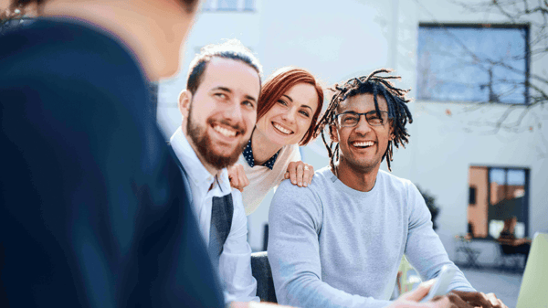 Three smiling people looking at another person