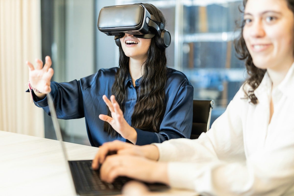 Two women working, one with a VR headset